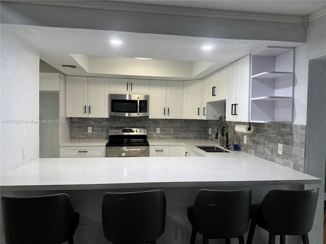 kitchen featuring sink, appliances with stainless steel finishes, white cabinets, and a breakfast bar area