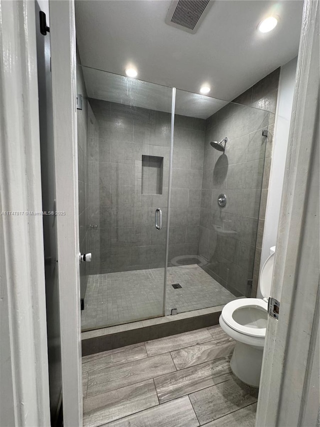 bathroom featuring a shower with shower door and toilet