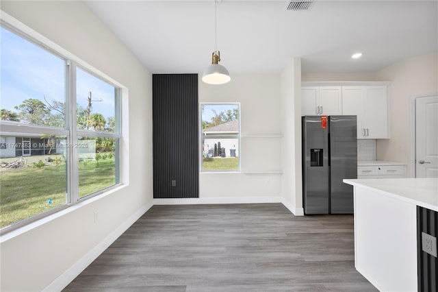 kitchen featuring white cabinets, pendant lighting, stainless steel fridge, and plenty of natural light