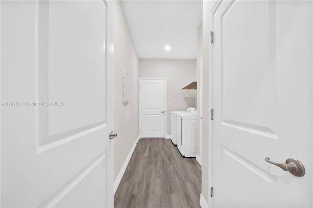 clothes washing area with washing machine and clothes dryer and light hardwood / wood-style flooring