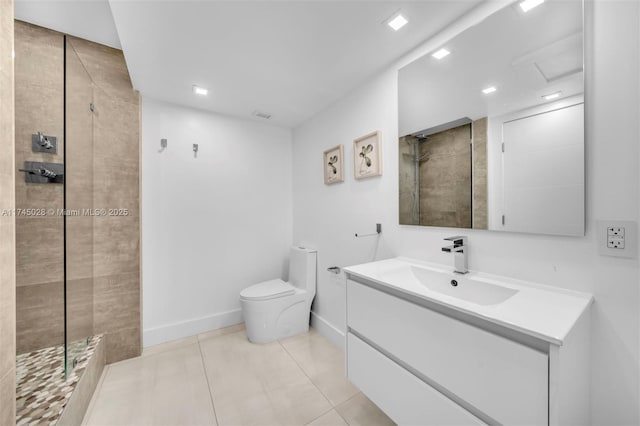 bathroom with tile patterned flooring, vanity, a tile shower, and toilet