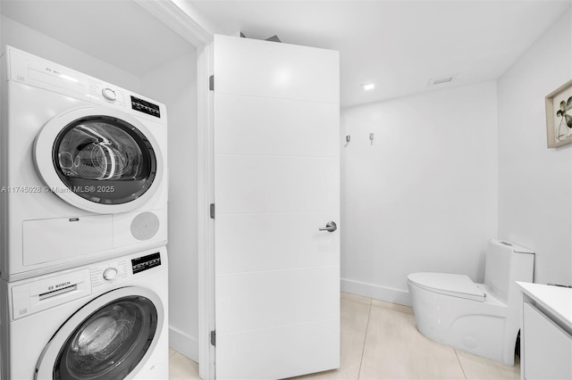 laundry room featuring stacked washer and clothes dryer and light tile patterned floors