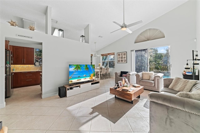 tiled living room with ceiling fan and high vaulted ceiling