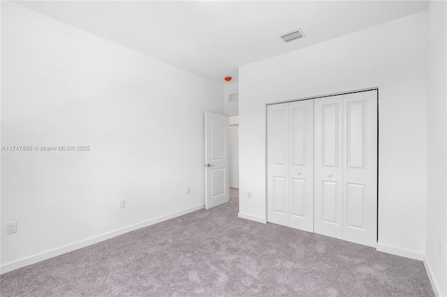 unfurnished bedroom featuring a closet and light colored carpet