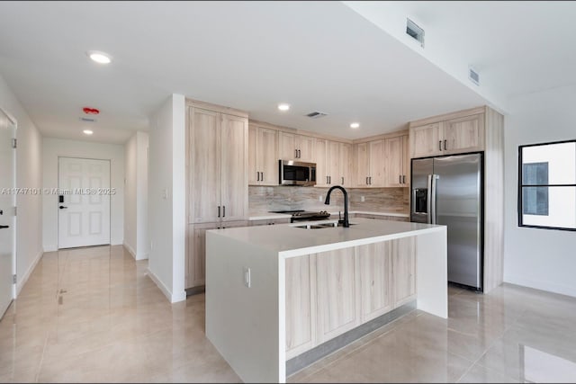 kitchen featuring tasteful backsplash, visible vents, light brown cabinets, appliances with stainless steel finishes, and a sink