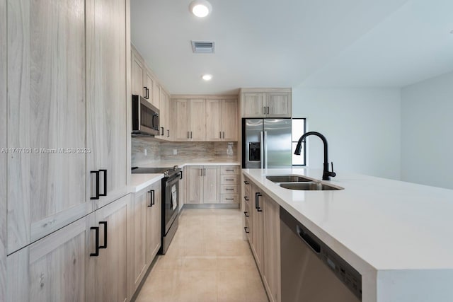 kitchen featuring decorative backsplash, appliances with stainless steel finishes, light countertops, and a sink