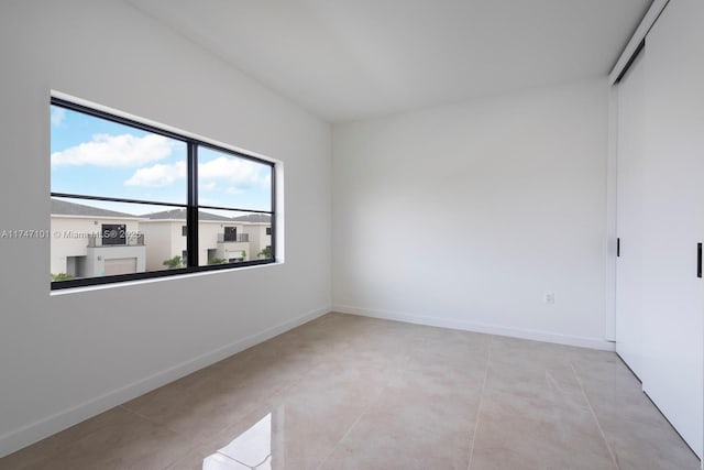 empty room featuring light tile patterned floors and baseboards