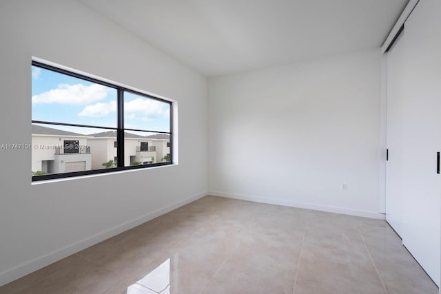 empty room with light tile patterned floors and baseboards