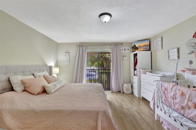 bedroom featuring light wood-type flooring, access to exterior, and a textured ceiling