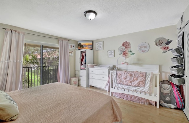 bedroom featuring light hardwood / wood-style floors, access to exterior, and a textured ceiling