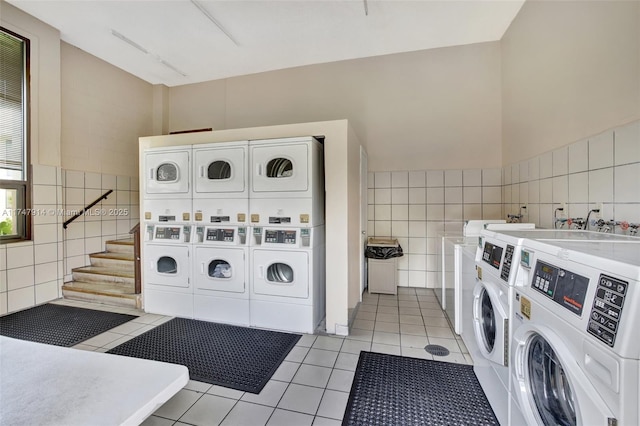 laundry area with tile walls, light tile patterned floors, independent washer and dryer, and stacked washer and clothes dryer