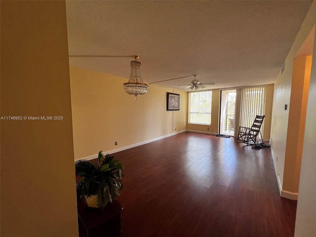 spare room with a wall of windows, dark wood finished floors, baseboards, and ceiling fan