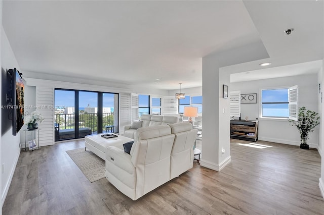 living area featuring visible vents, baseboards, a chandelier, and wood finished floors