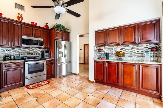 653 NW 110th Ave, Coral Springs, FL 33071 - kitchen with light tile patterned flooring, appliances with stainless steel finishes, light stone counters, and decorative backsplash