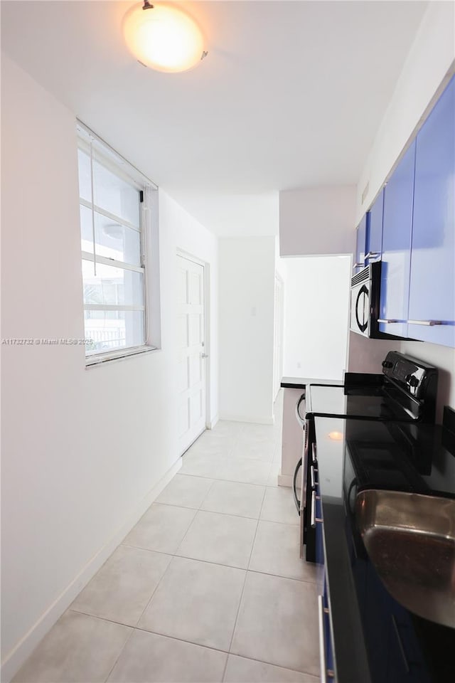 kitchen featuring light tile patterned flooring, blue cabinets, and black / electric stove