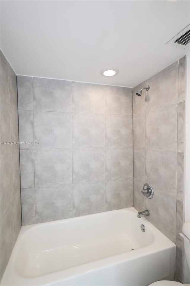 bathroom featuring toilet and tiled shower / bath