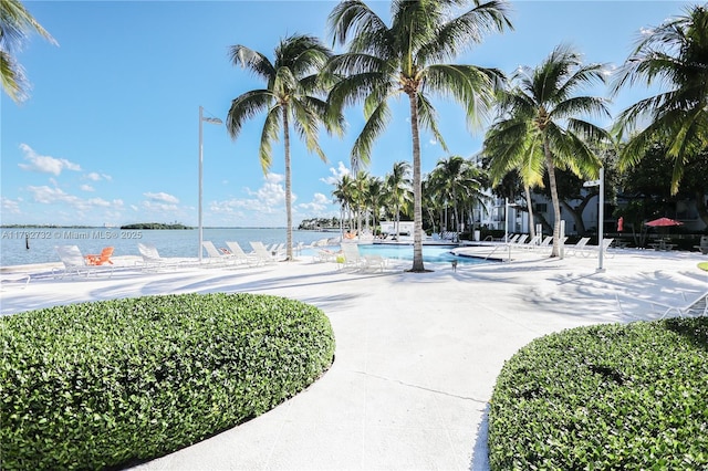 surrounding community featuring a water view, a swimming pool, and a patio area