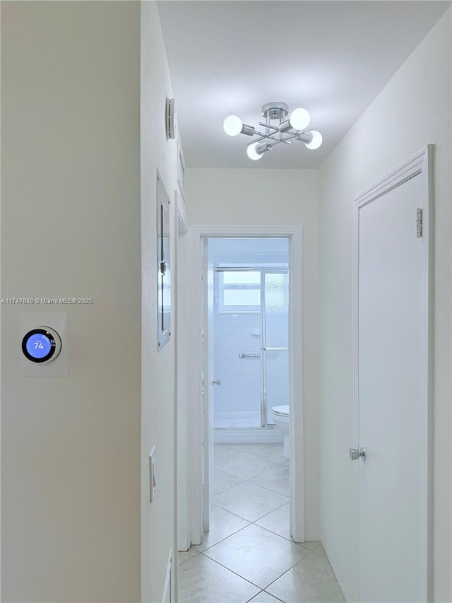 corridor featuring baseboards, an inviting chandelier, and light tile patterned floors