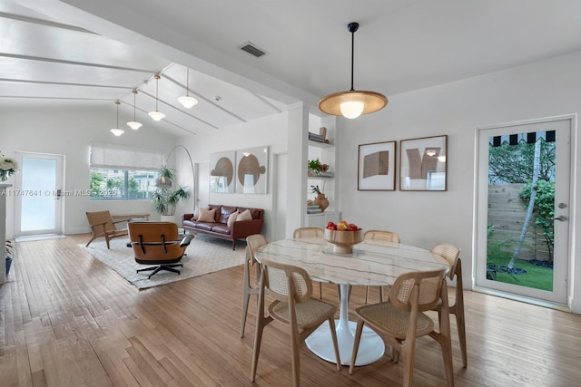 dining area with vaulted ceiling with beams and light hardwood / wood-style flooring