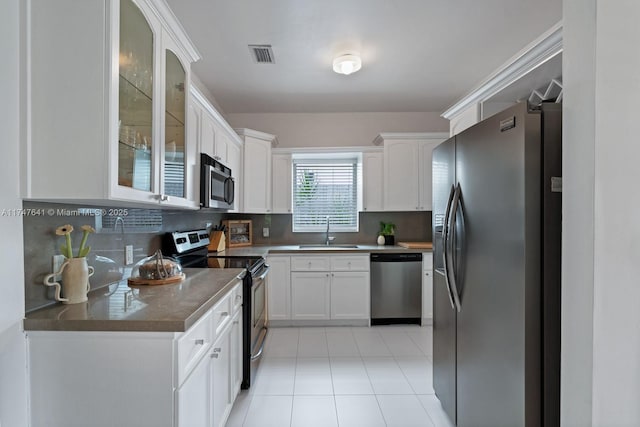 kitchen featuring appliances with stainless steel finishes, tasteful backsplash, light tile patterned floors, sink, and white cabinetry