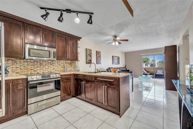 kitchen with appliances with stainless steel finishes, tasteful backsplash, dark brown cabinetry, light tile patterned floors, and kitchen peninsula