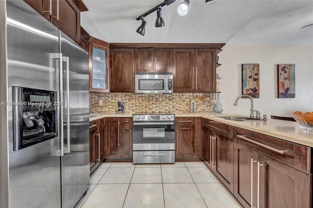 kitchen with sink, a textured ceiling, stainless steel appliances, and decorative backsplash