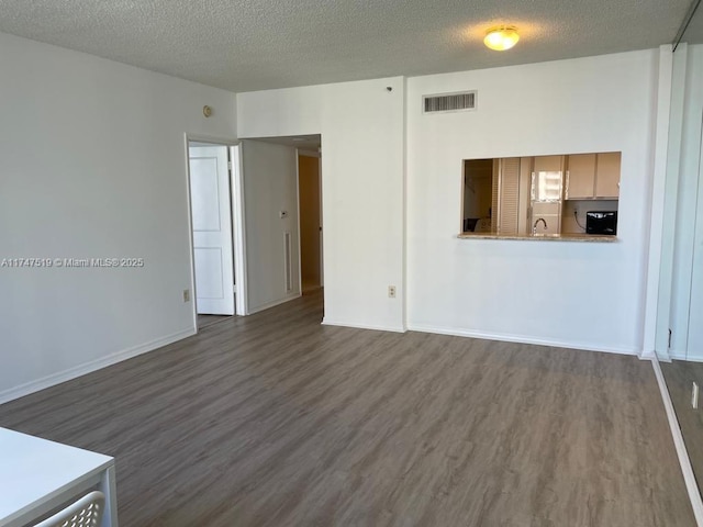 unfurnished living room featuring sink, dark wood-type flooring, and a textured ceiling