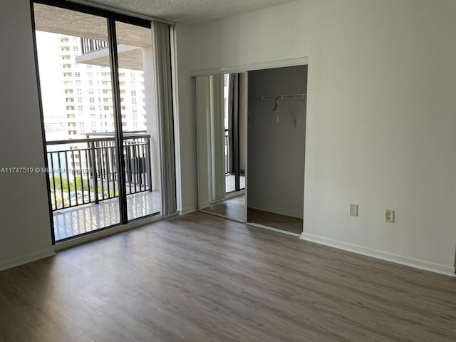 interior space with a wall of windows, hardwood / wood-style flooring, access to exterior, and a textured ceiling