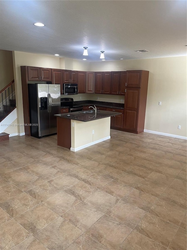 kitchen featuring appliances with stainless steel finishes, sink, a kitchen breakfast bar, dark stone counters, and an island with sink