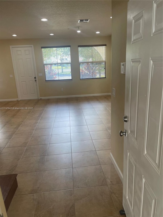 tiled empty room featuring a textured ceiling