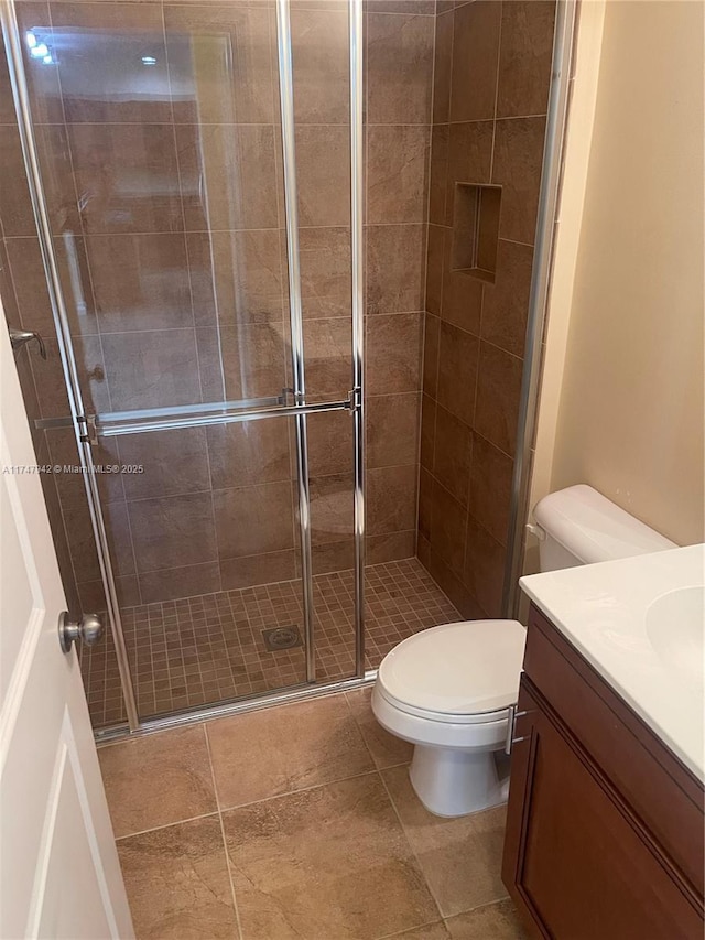 bathroom featuring vanity, a shower with door, and toilet