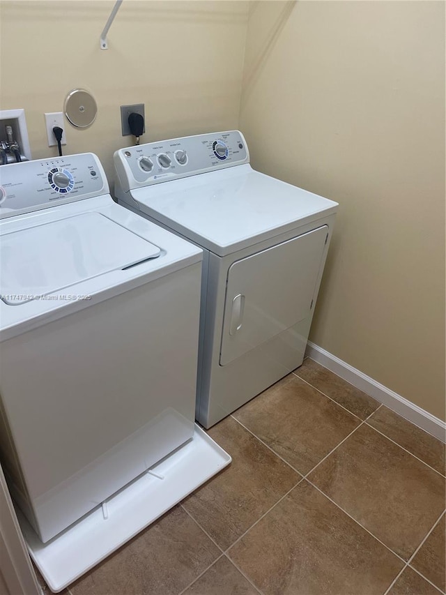 clothes washing area with dark tile patterned floors and washing machine and clothes dryer