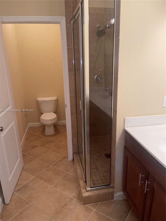 bathroom with tile patterned floors, toilet, a shower with door, and vanity