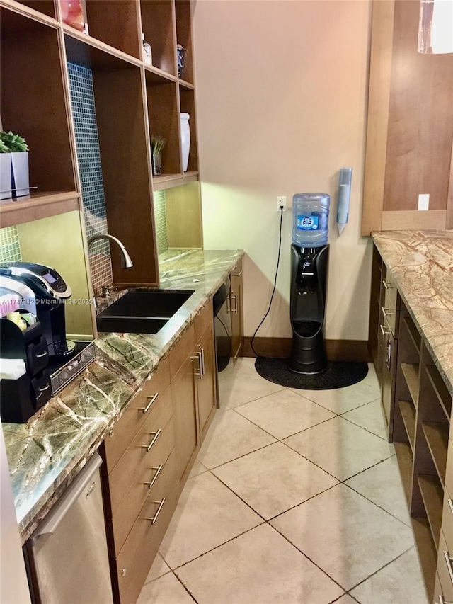 kitchen with light tile patterned flooring, light stone countertops, dishwasher, and sink