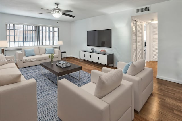 living area featuring visible vents, baseboards, and wood finished floors