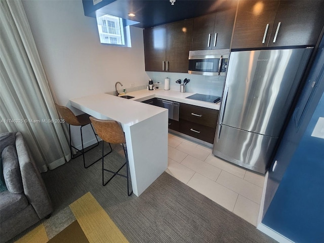 17315 Collins Ave Unit 1506, Sunny Isles Beach, FL 33160 - kitchen featuring appliances with stainless steel finishes, a kitchen breakfast bar, dark brown cabinetry, a peninsula, and light countertops