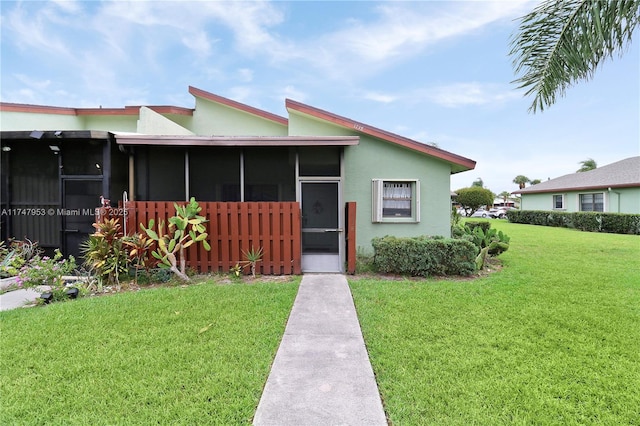 view of front of property with a sunroom, a front lawn, and stucco siding