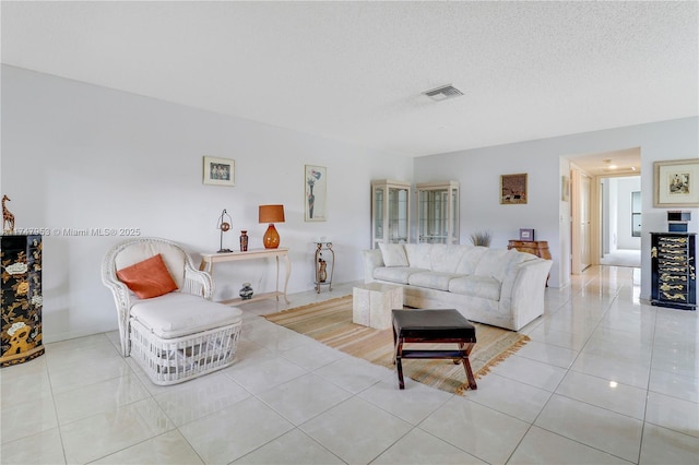 living room featuring visible vents, a textured ceiling, and tile patterned floors