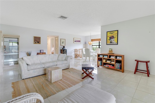 living room featuring visible vents, a textured ceiling, an inviting chandelier, and light tile patterned floors