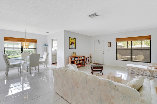 living room featuring light tile patterned floors, visible vents, a wealth of natural light, and an inviting chandelier