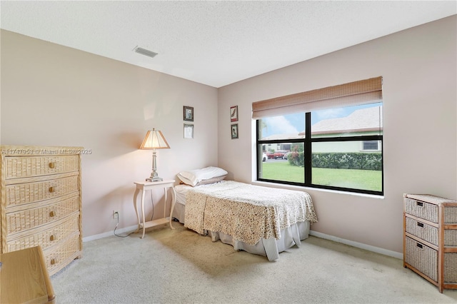 carpeted bedroom featuring baseboards, visible vents, and a textured ceiling