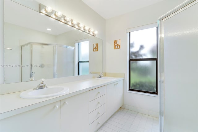 full bathroom with double vanity, a stall shower, tile patterned flooring, and a sink