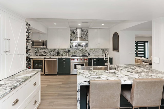 1301 Adams St, Hollywood, FL 33019 - kitchen featuring white cabinetry, wall chimney range hood, a breakfast bar area, and stainless steel appliances