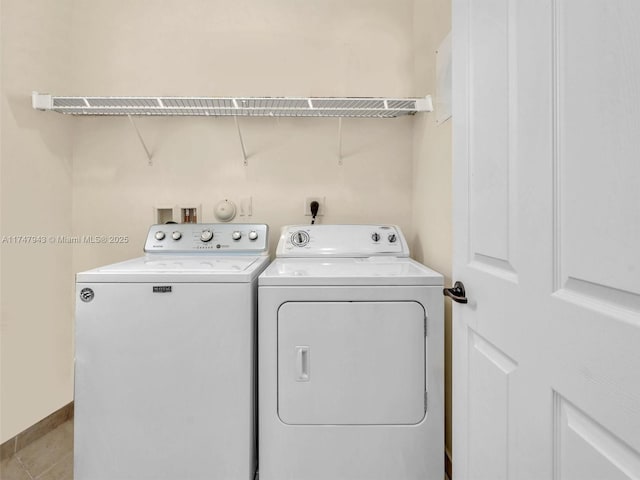 clothes washing area featuring washer and dryer and light tile patterned floors