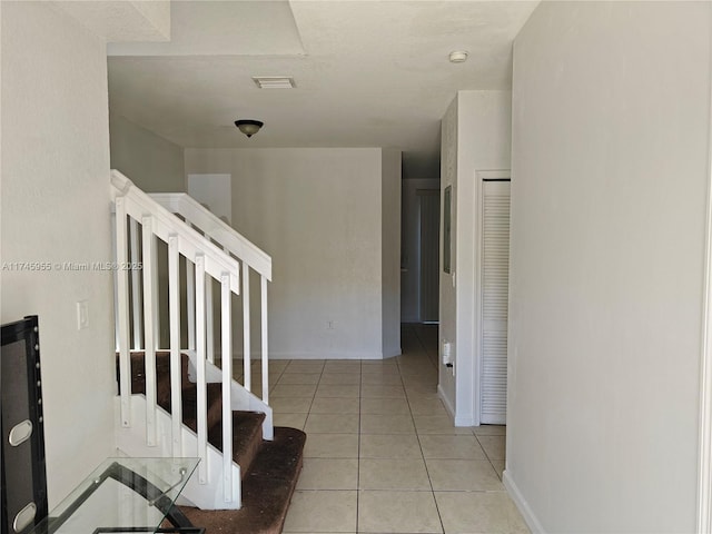 stairs featuring baseboards, visible vents, and tile patterned floors