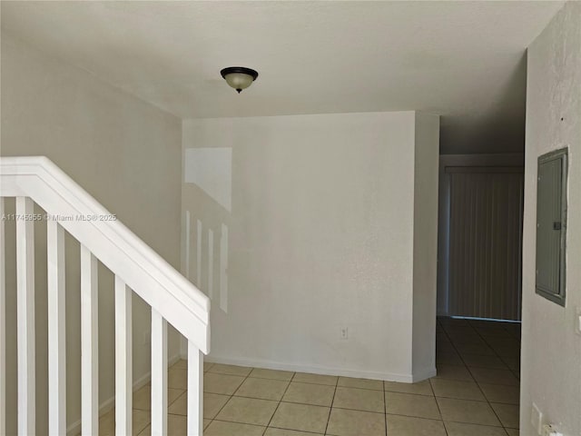 interior space featuring light tile patterned floors, electric panel, and baseboards