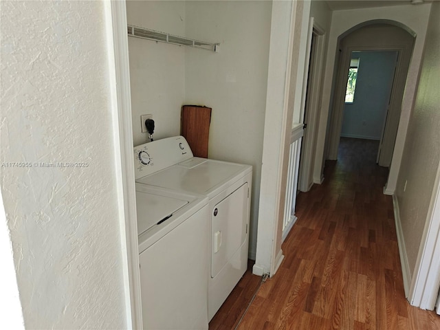 washroom with dark wood-style floors, baseboards, arched walkways, and separate washer and dryer