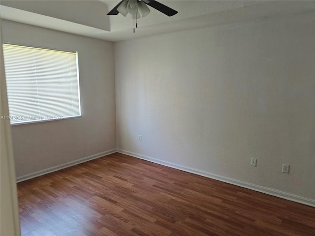 unfurnished room featuring dark wood-style floors, ceiling fan, and baseboards