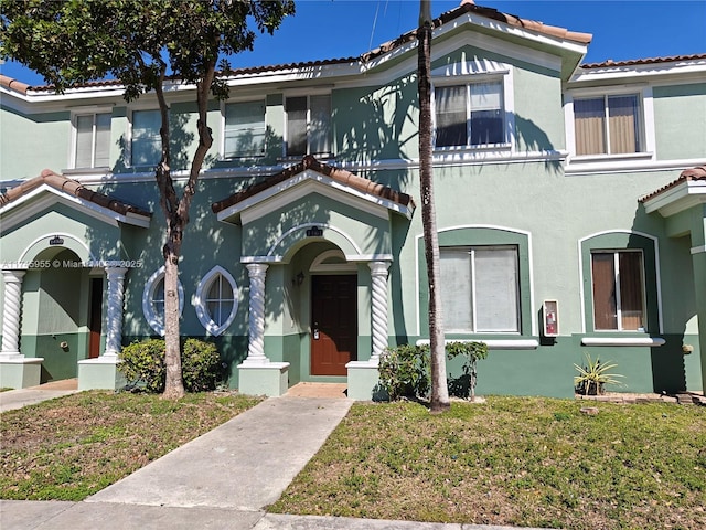 mediterranean / spanish-style house with a tiled roof, a front lawn, and stucco siding