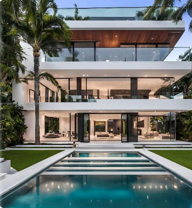 rear view of property featuring a balcony, a patio area, and an outdoor pool